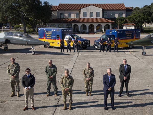 Military and emergency personnel posed between fighter jets and emergency vehicles.
