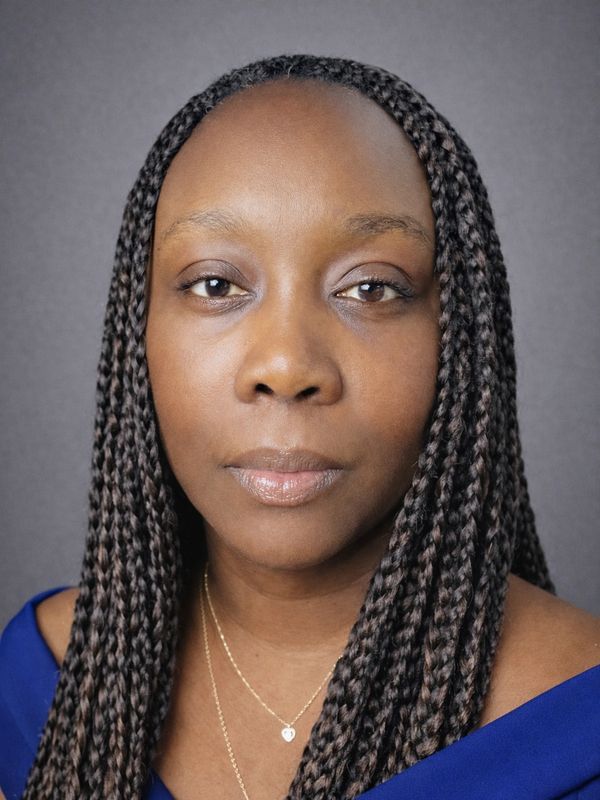 Portrait of a woman with long braided hair and a blue top.