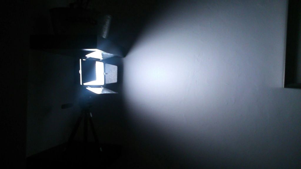 Bright studio light projecting on a blank wall in a dark room.