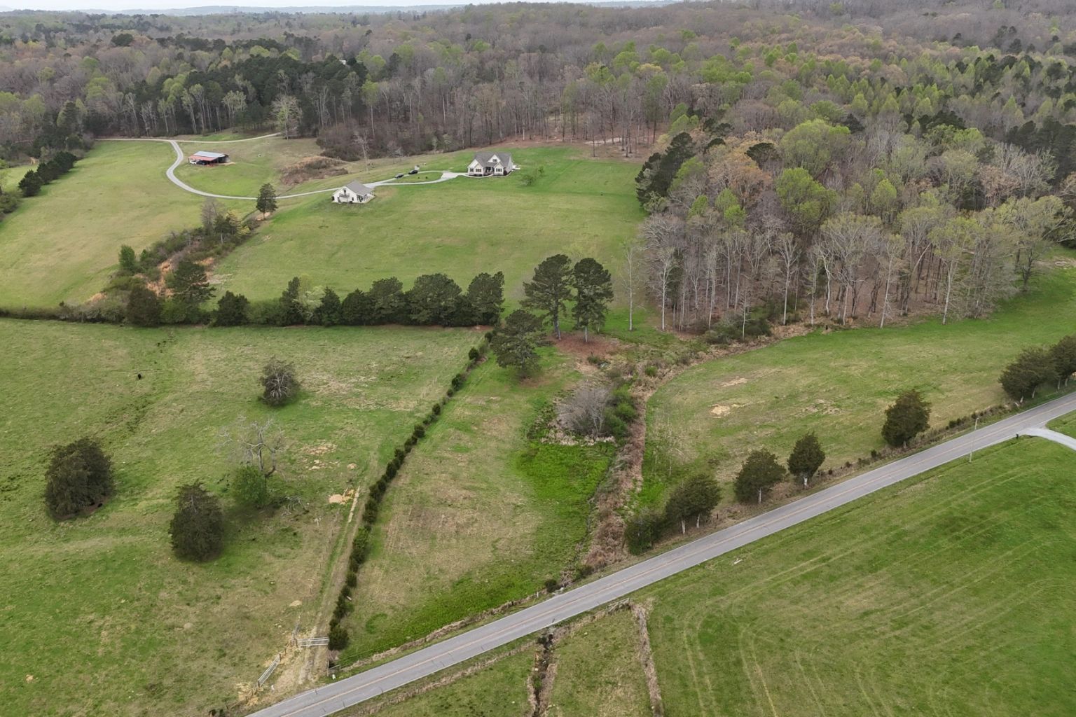 Aerial view of a rural landscape with houses, trees, and a road.