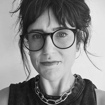 Black and white portrait of a woman with glasses and piercings.