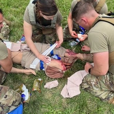 Military personnel performing first aid on a wounded soldier.