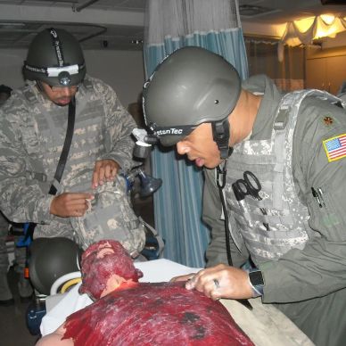 Military personnel treating a severely injured patient.