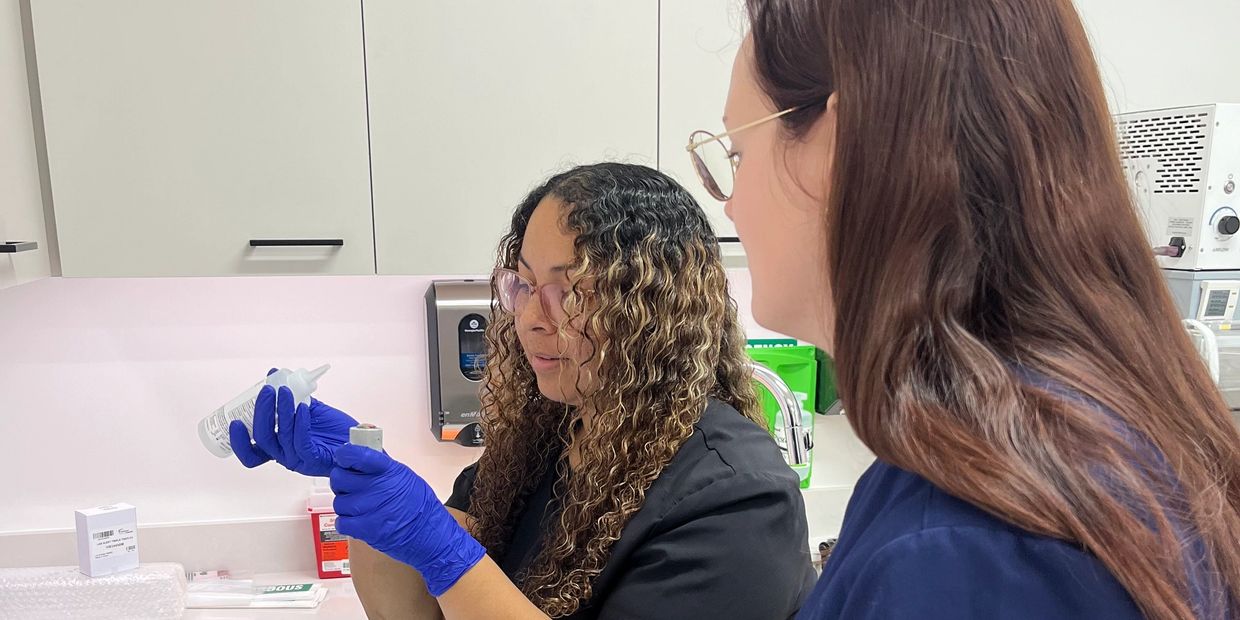 Two women working in a lab with gloves and equipment.