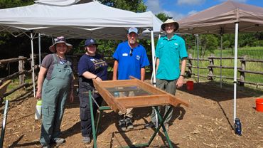 A group of NTAS volunteers stands next to a screening tool.