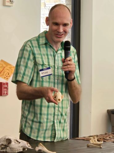 An NTAS volunteer shows an animal skull while holding a microphone.