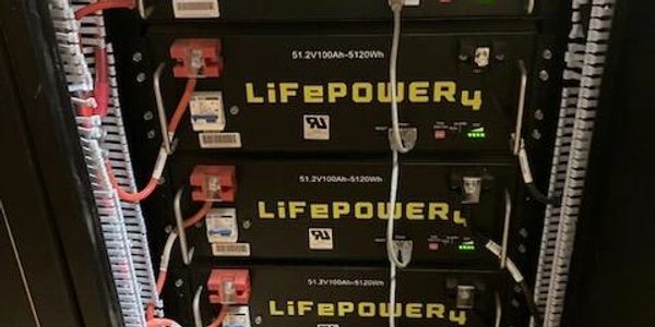 Stacked LiFePOWER4 batteries in a rack with wiring connections.