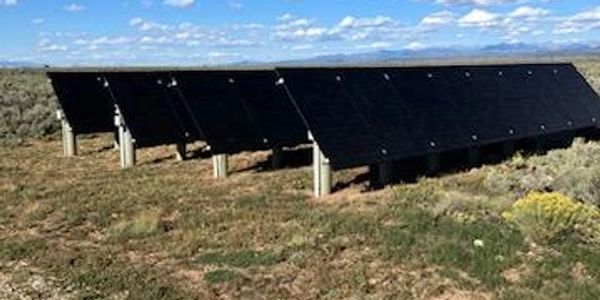 Solar panels installed in a sunny, open field under a clear blue sky.