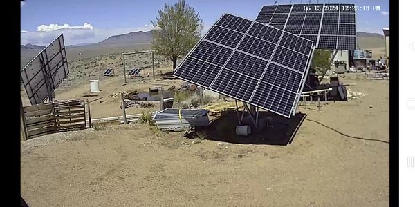 Solar panels installed in a desert area with mountains in the background.