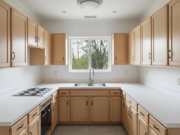 Clean kitchen with wooden cabinets and white countertops.