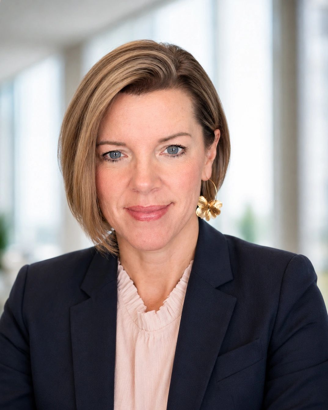 Professional woman in business attire with flower earring.