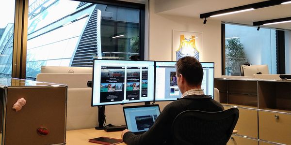 Alpha Experience Design working in the office with design displayed on large monitors. 