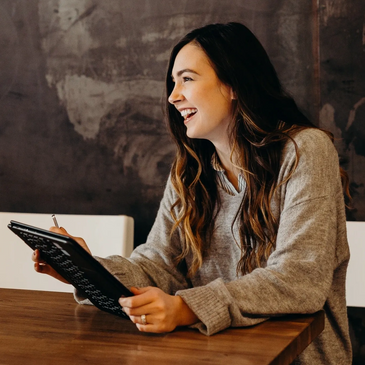 Photography of a customer sitting at a table using a tablet computer.