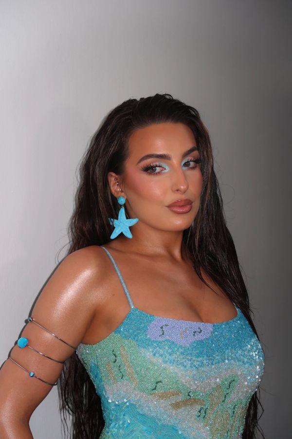 Woman in a sparkly aqua dress with starfish earrings.