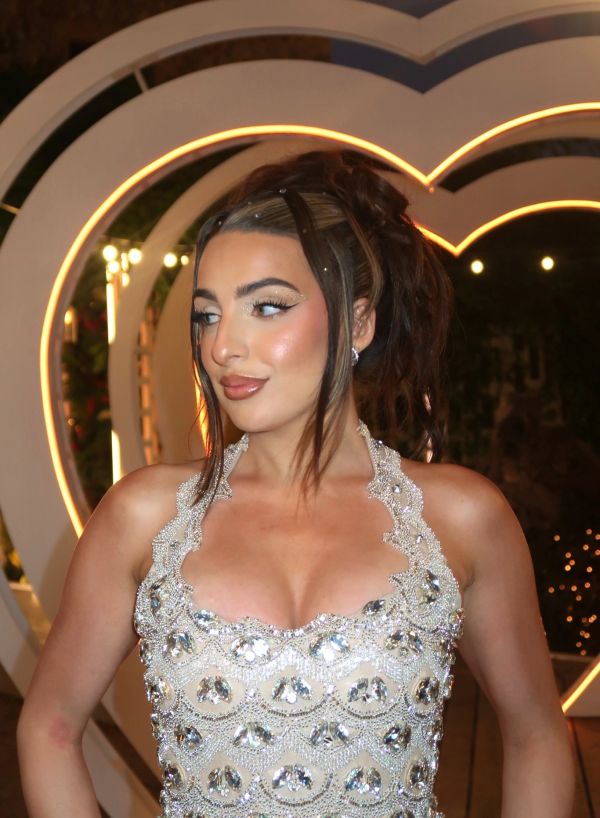 Woman in a sparkling dress with heart-shaped lights behind.