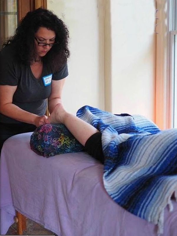 Woman massaging someone's foot on a massage table.