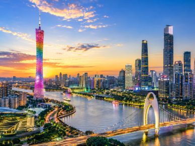 City skyline with a colorful tower and river at sunset.