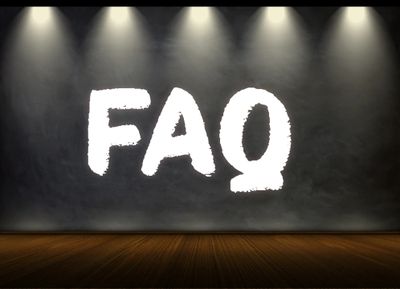 Large white FAQ letters illuminated on dark wall with wooden floor.