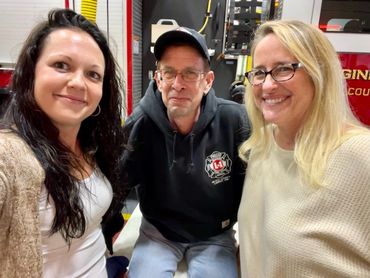 Three smiling people posing indoors.