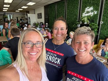 Three women smiling inside a cafe.