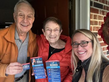 Three people holding campaign flyers and smiling.
