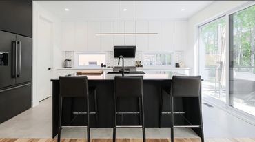 Modern kitchen with black and white contrast and large window.
