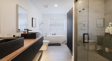 Modern bathroom with black fixtures, wood countertop, and a freestanding bathtub.