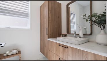 Modern bathroom with wooden cabinetry and a large mirror.