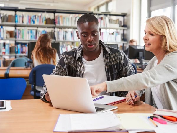 Two people working at laptop.