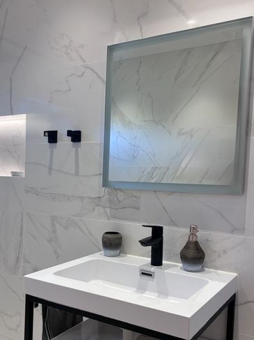 Modern bathroom sink with black faucet and marble walls.
