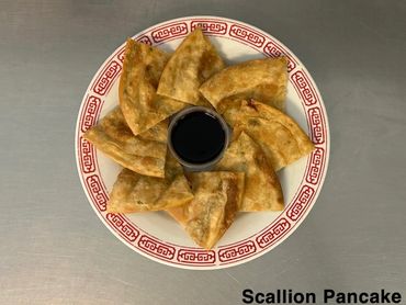 Crispy scallion pancakes arranged around a soy sauce dipping cup on a plate.