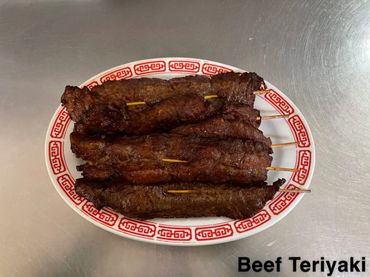 Grilled beef teriyaki skewers on a decorative plate.