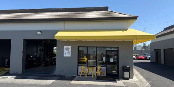 Flat Rate Mechanix auto repair shop entrance with yellow awning and outdoor seating in Las Vegas