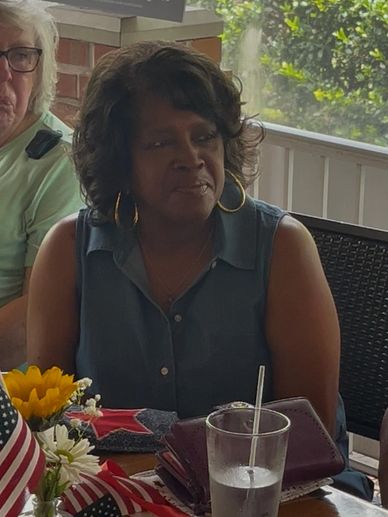 Woman sitting at a table with patriotic decorations and flowers.