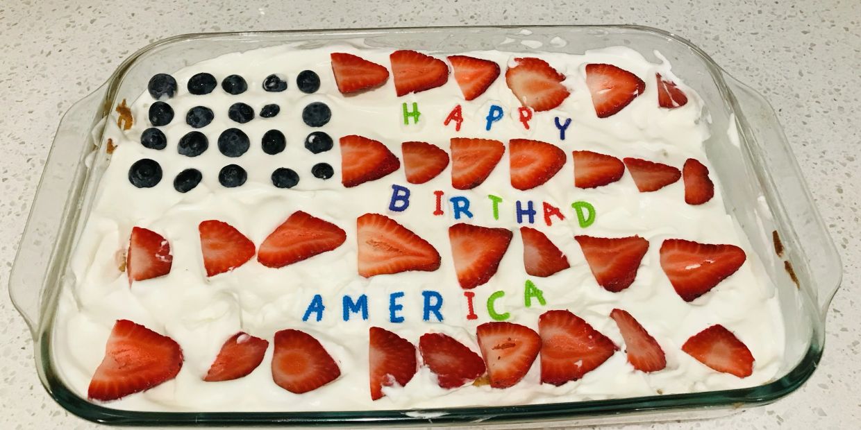 A patriotic birthday dessert decorated with strawberries and blueberries.