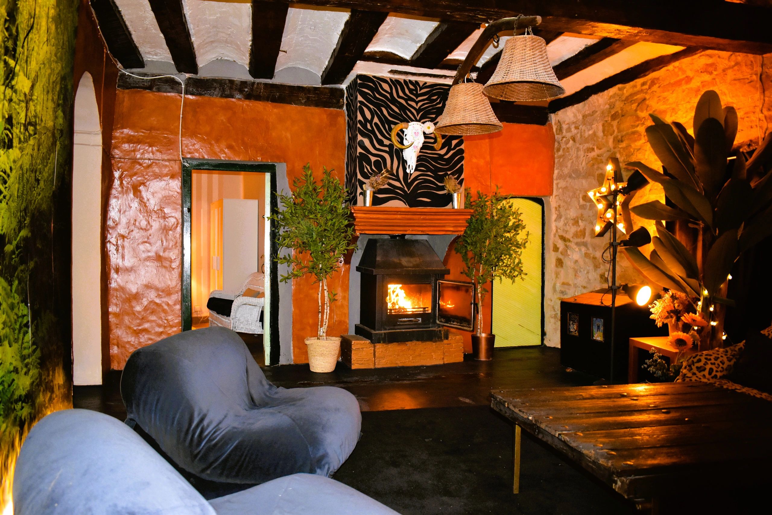 Sala rústica con chimenea encendida y decoración cálida.