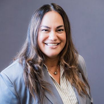 Smiling woman with long hair in a gray blazer.