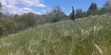 Person standing on a grassy hill under a partly cloudy sky.