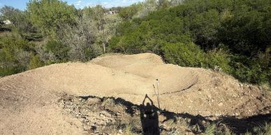 A dirt bike trail with mounds and curves in a natural setting.