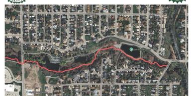 A satellite map showing a river with a red trail running alongside it through a residential area.