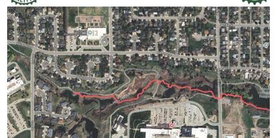 Aerial view of a suburban neighborhood with a red line marking a trail through a green area.