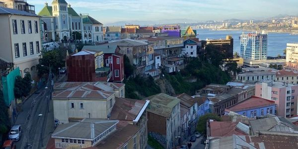A scenic hillside cityscape with colorful buildings overlooking the water.