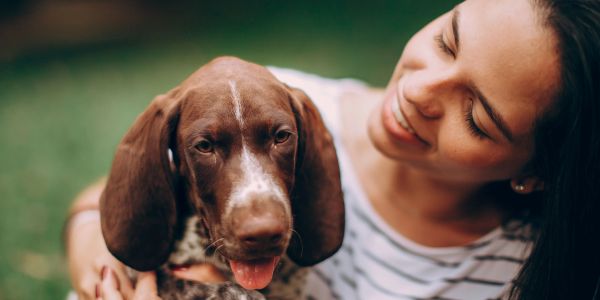 Femme souriante avec un chien brun.
