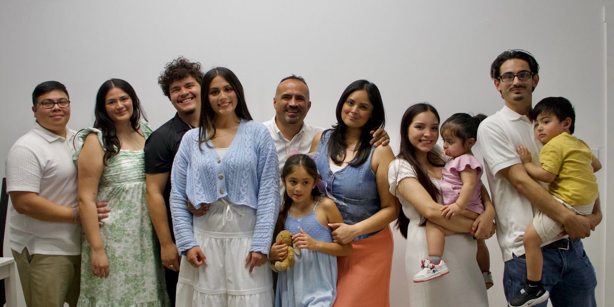 A happy family group posing together against a plain white wall.