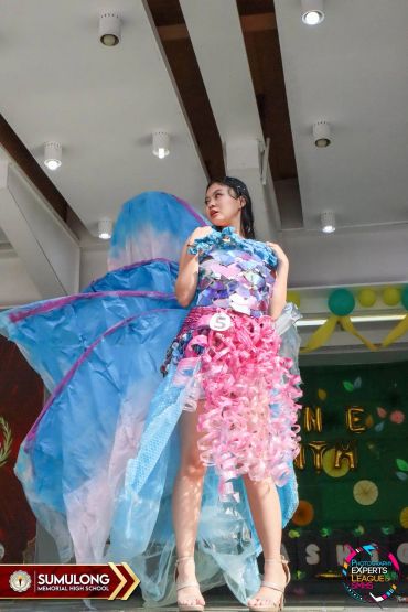 A young woman in a colorful, creative butterfly costume on stage.