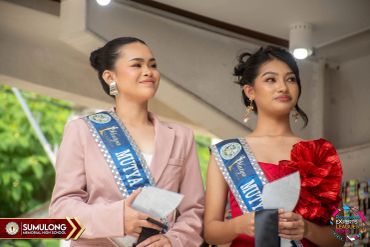Two young women wearing sashes at a formal event.