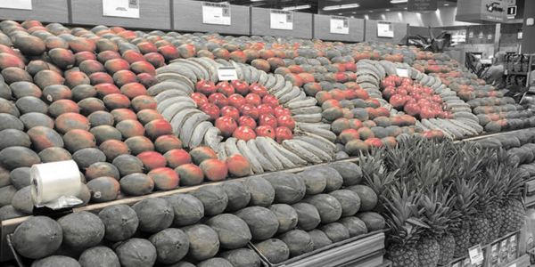 Colorful watermelons and pineapples arranged in a grocery store display.
