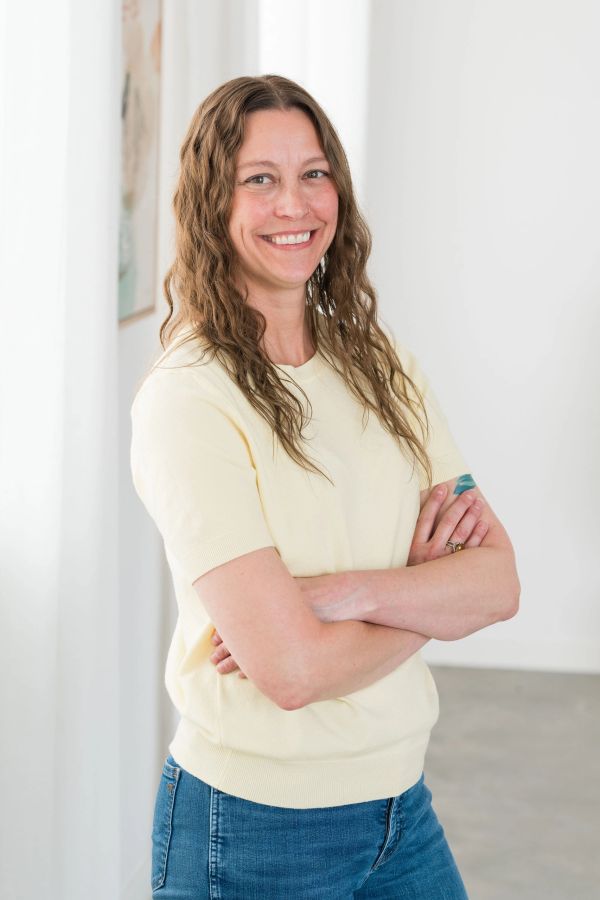Smiling woman with crossed arms in casual clothing.