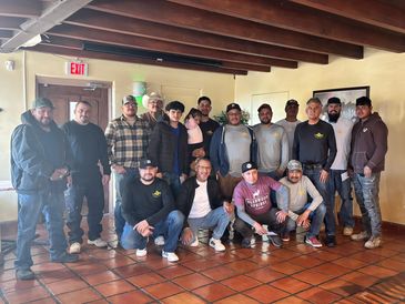 Group of men posing indoors with wooden ceiling beams.