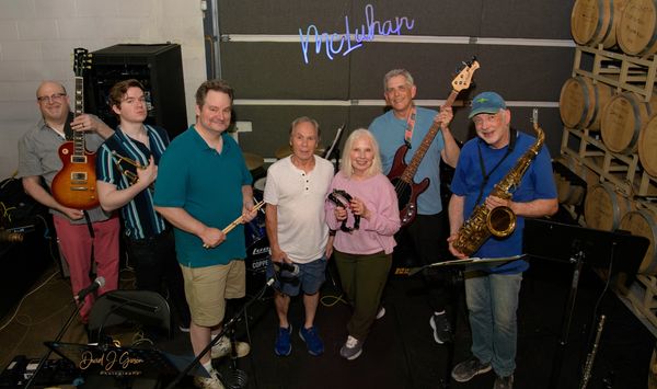 McLuhan band poses for a photo.  Seven musicians with instruments.